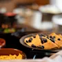 Pannekaker toppes med friske blåbær, servert på en tallerken blant ulike retter på et buffetbord i en spisestue.