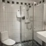 Et rent og moderne hotellbad med toalett, en dusjkabinett i glass og en vask med toalettartikler.