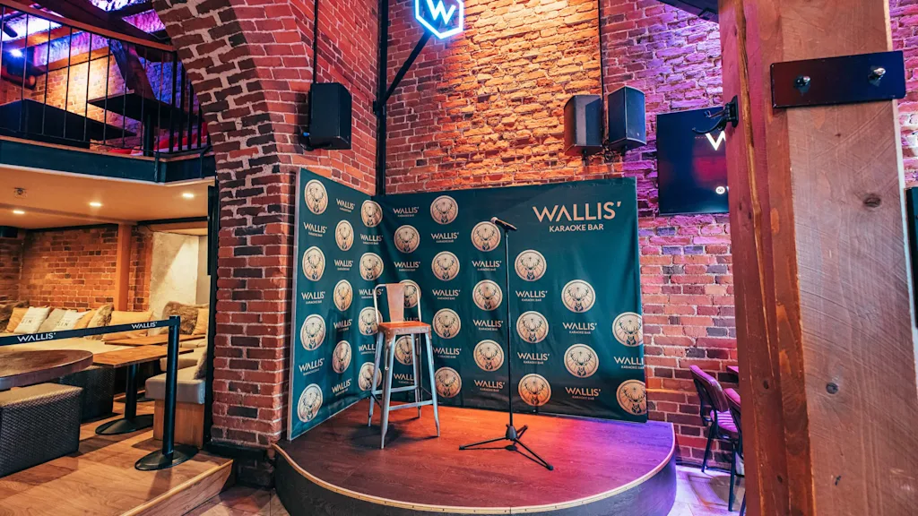 En karaokescen med mikrofon och pall, med 'KARAOKE BAR' som bakgrund, på Wallis' Skatta Karaoke Bar i Helsingfors.