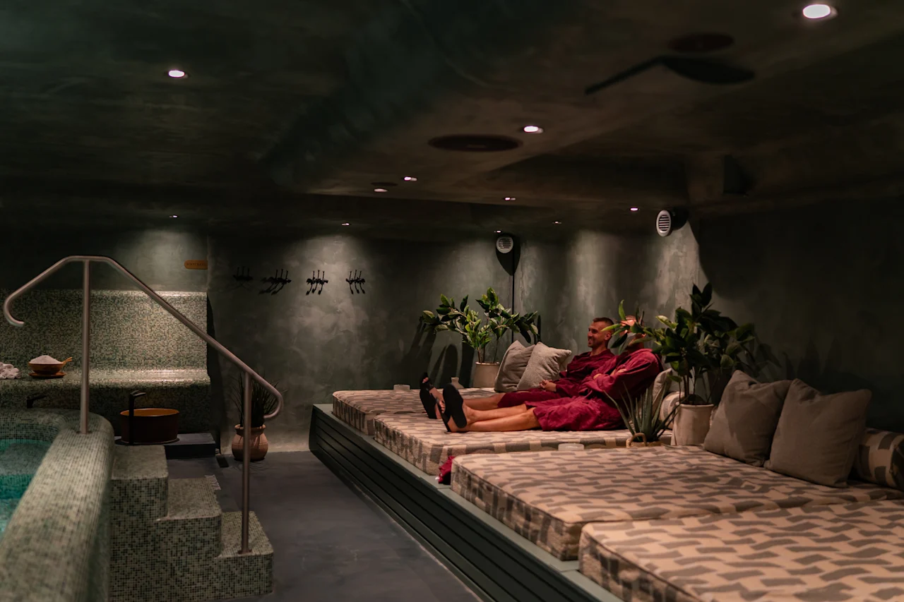 Rauhallinen kylpylän rentoutumisalue, jossa henkilö rentoutuu mukavalla leposängyllä rauhallisen uima-altaan vieressä.