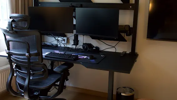 Moderne hjemmekontor med to computerskærme, ergonomisk kontorstol og et stort skrivebord.