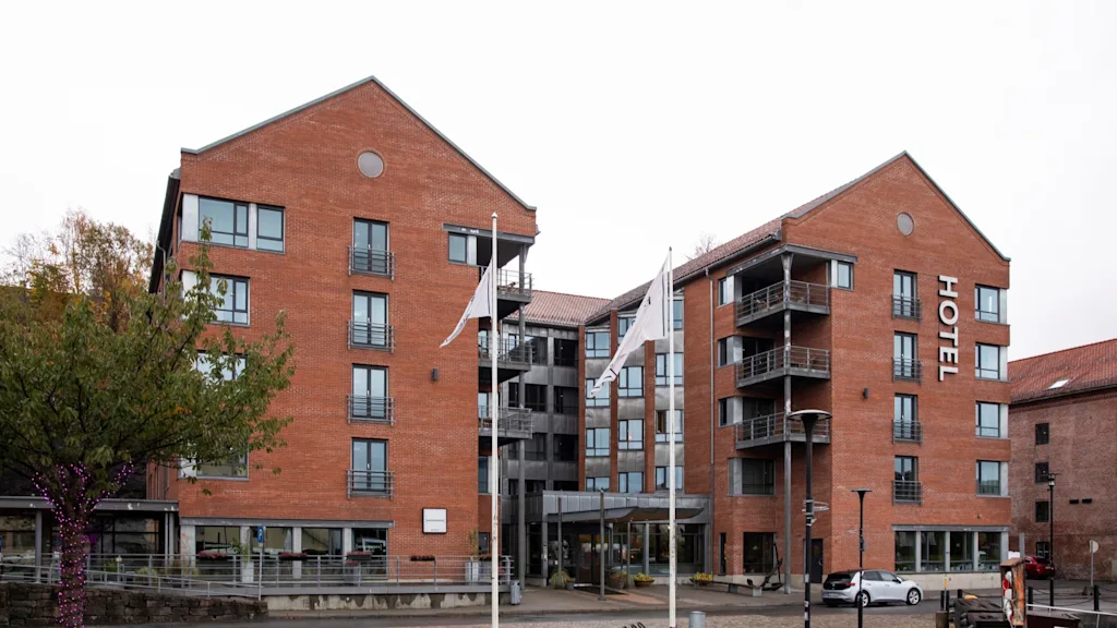 A modern brick hotel building with balconies and large windows, featuring a prominent "HOTEL" sign.