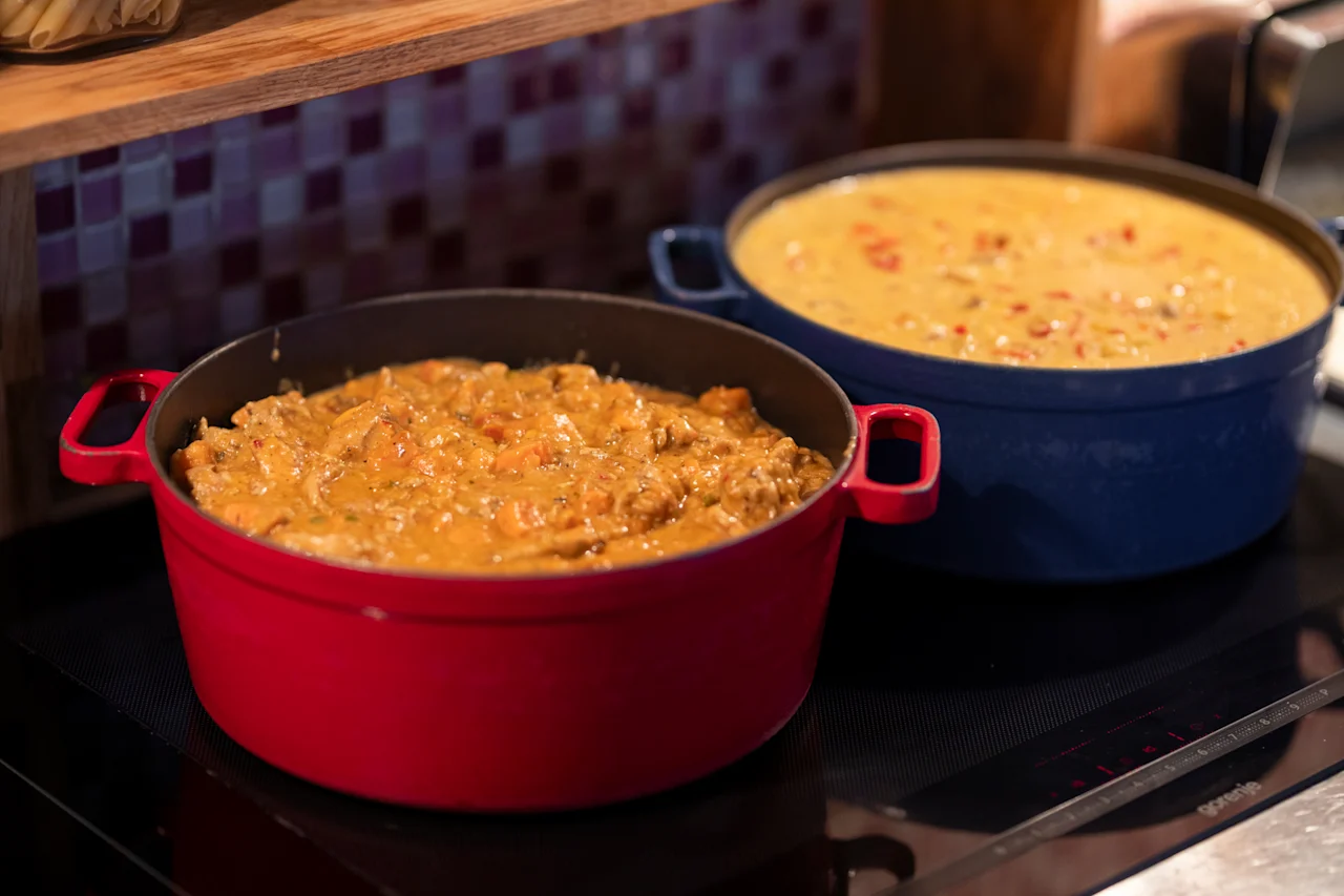 Kaksi värikästä kattilaa täynnä herkullisen näköistä ruokaa porisemassa liedellä, valmiina tarjoiltavaksi.
