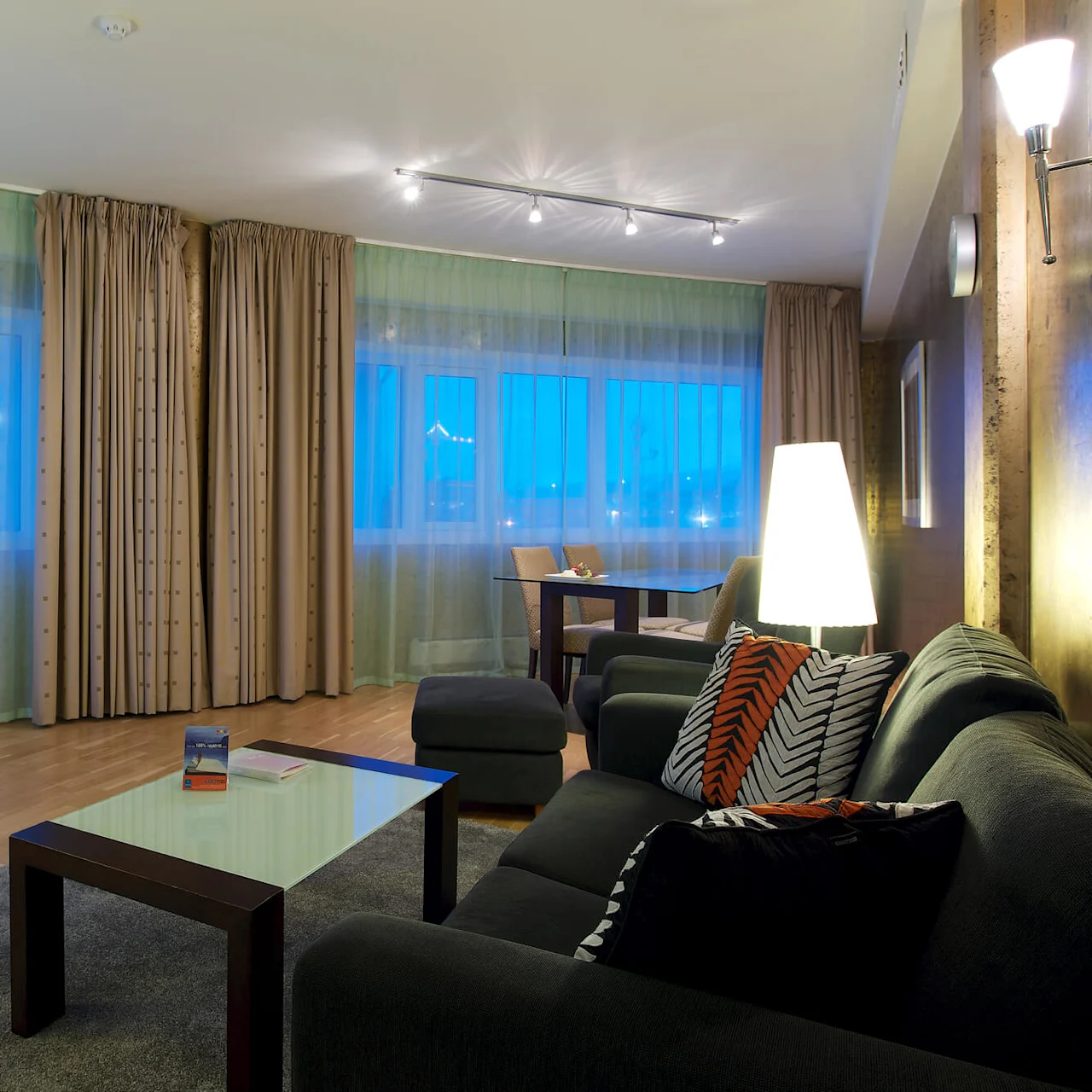 A well-lit, modern living room with furniture and large windows, suggesting a comfortable, stylish interior space.