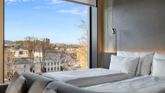 Deluxe rom på Comfort Hotel Porsgrunn med en koselig seng og et stort vindu som tilbyr utsikt over byen.