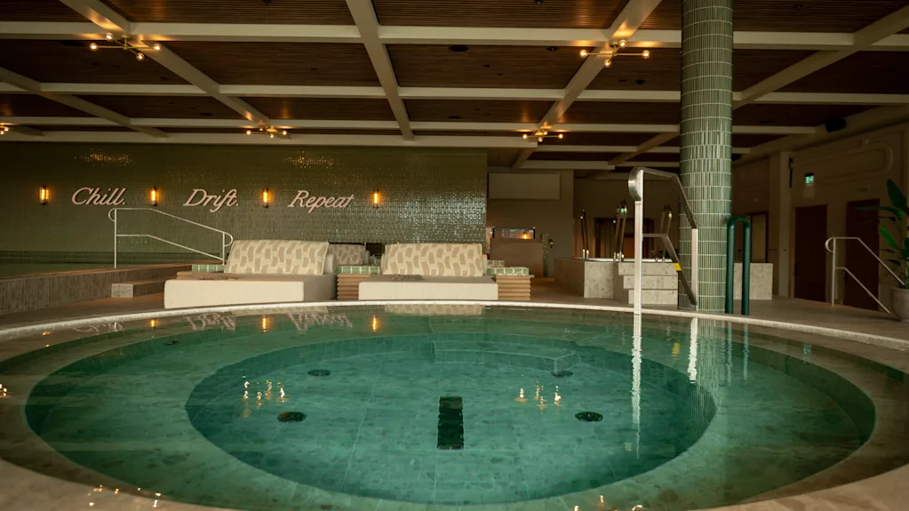 Et rolig syn av The Dock Spa med et stort sirkulært basseng, innbydende salongområder og mottoet 'Chill Drift Repeat'.