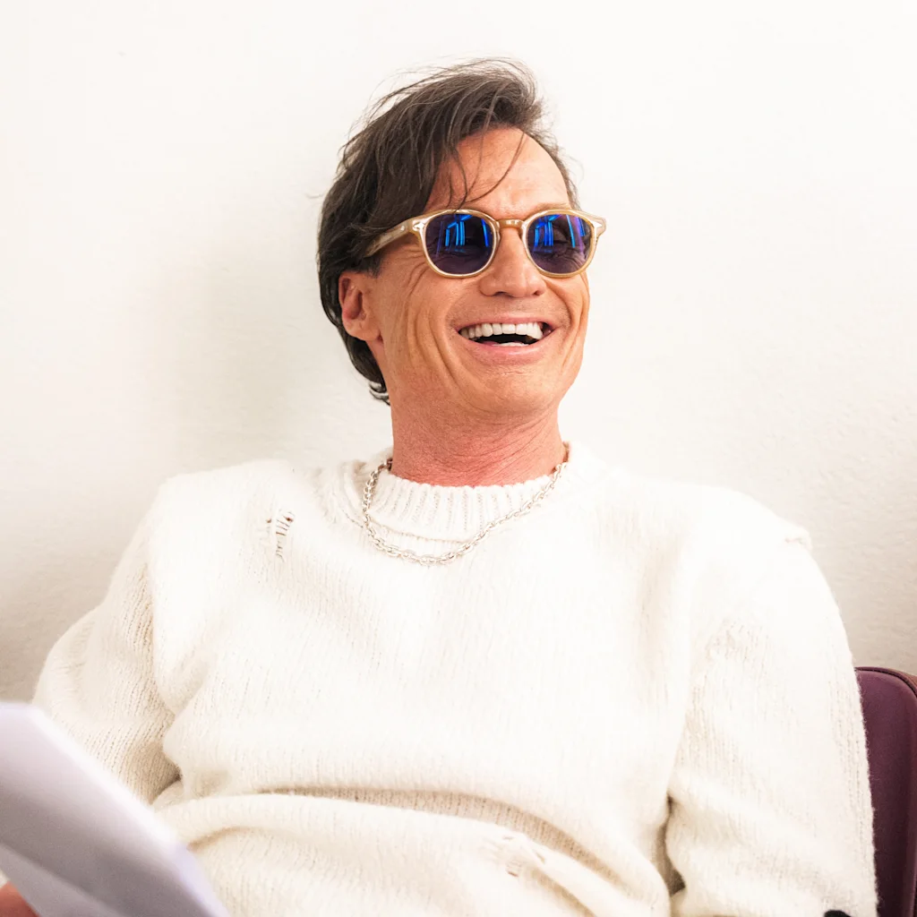 Petter Stordalen fra Strawberry smiler og bærer solbriller, holder papirer og ser engageret ud.