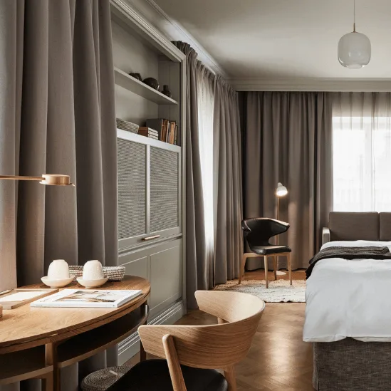 Stilfuldt hotelværelse med nyredt seng, træmøbler og hyggelig belysning; varm og indbydende atmosfære.