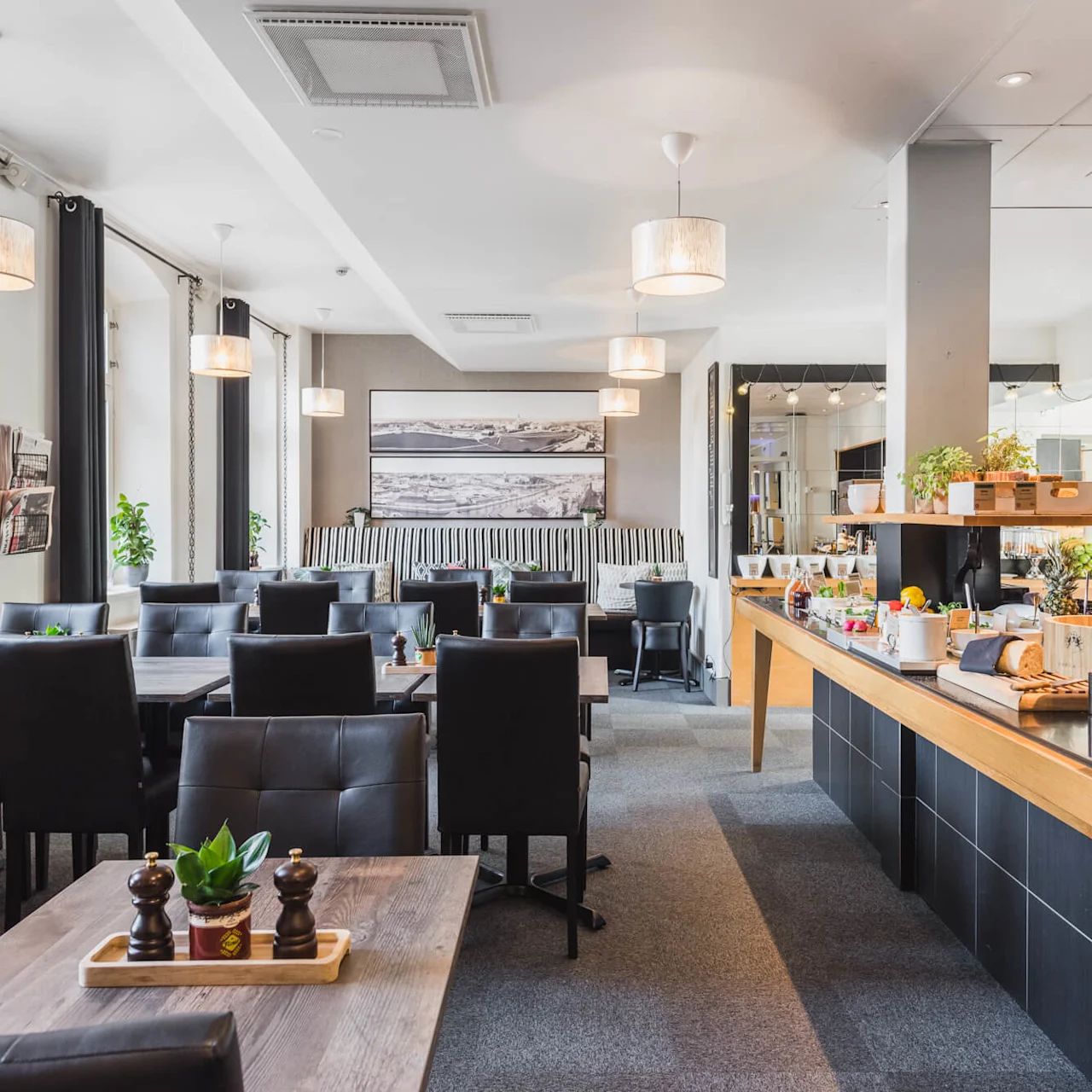 An empty restaurant interior with tables, chairs, and a buffet setup, ready to serve.