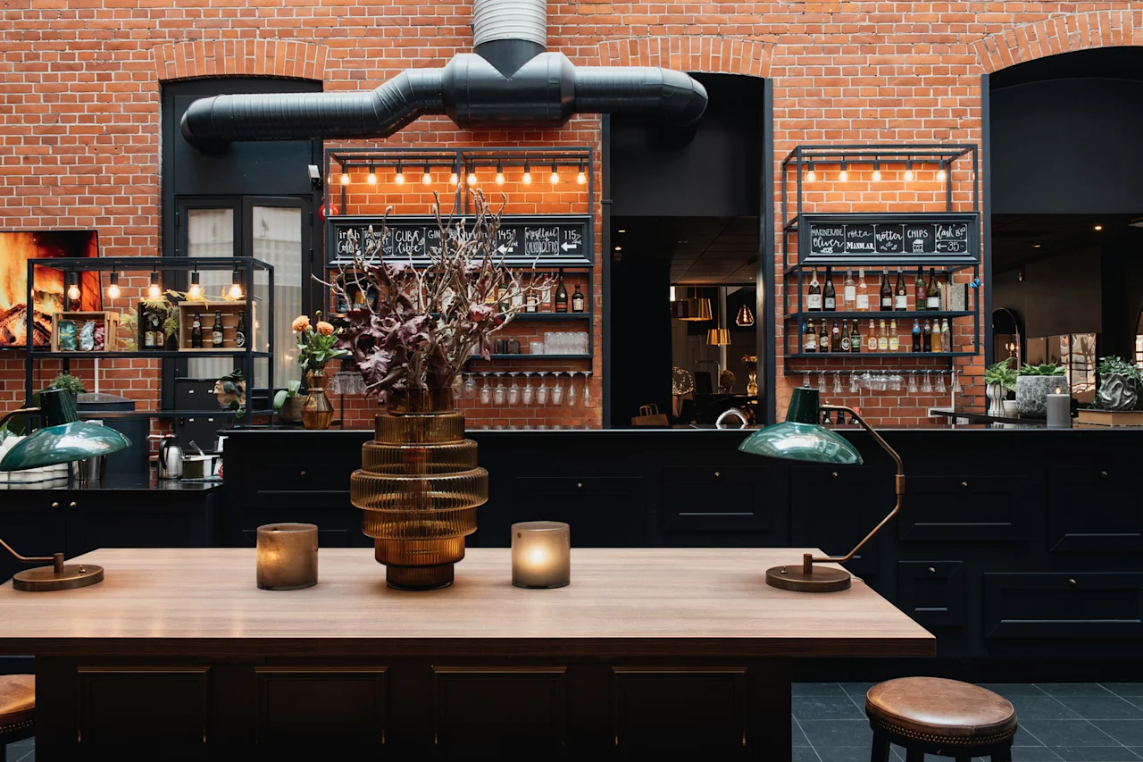 Koselig bar eller lounge med trebord, levende lys, murvegger. Tekst: CUBA GIN, OLIVER MARMAR, CHIPS, LAK UP, 145, 115, 30.