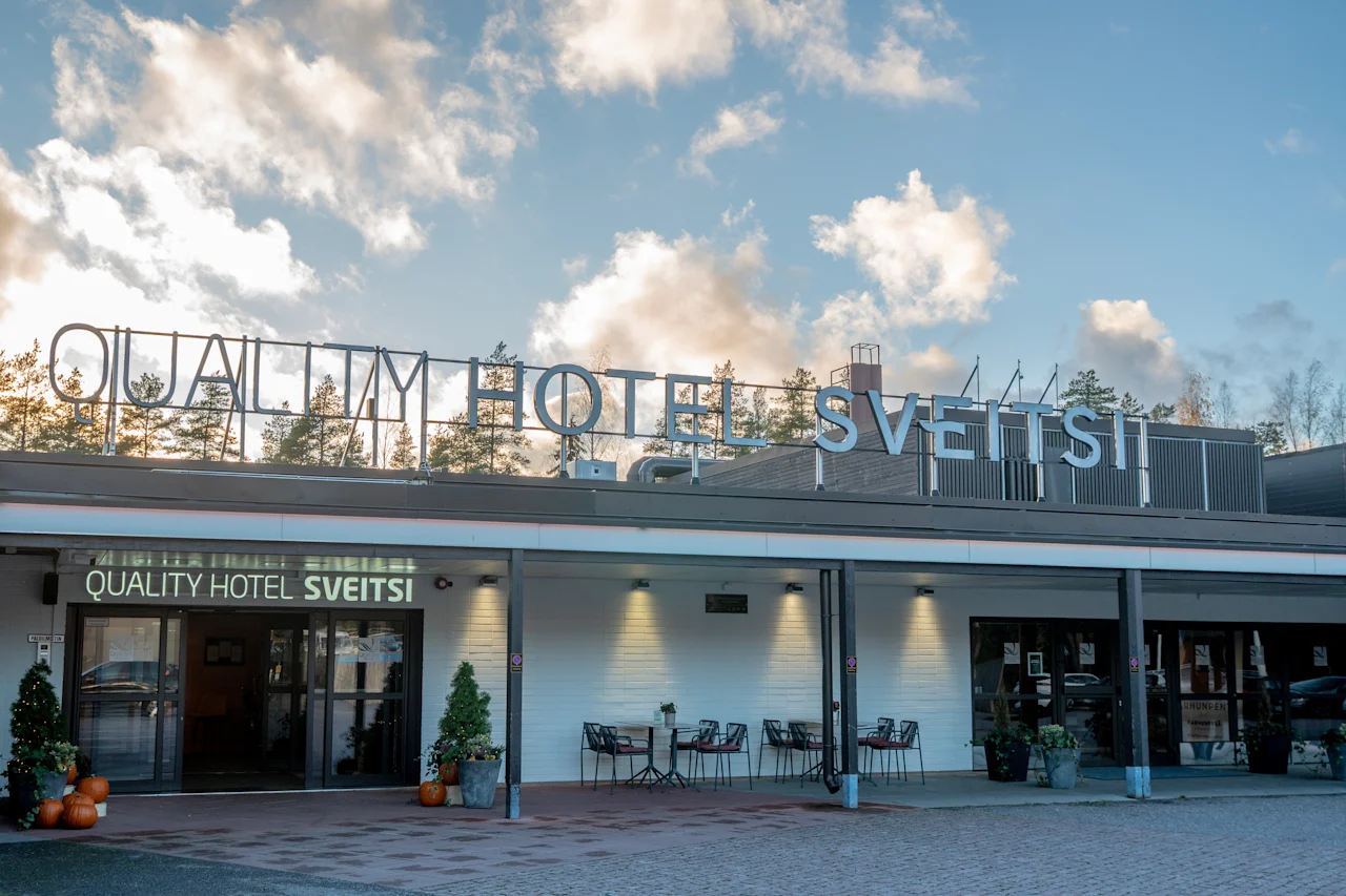 En indbydende udsigt over Quality Hotel Sveitsis eksteriør, med udendørs siddepladser og sæsonbetonede dekorationer under en skyet himmel.