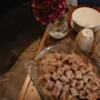 A table laden with delicious-looking pastries, a vase of red flowers, and stacks of plates and cups, ready for a gathering.
