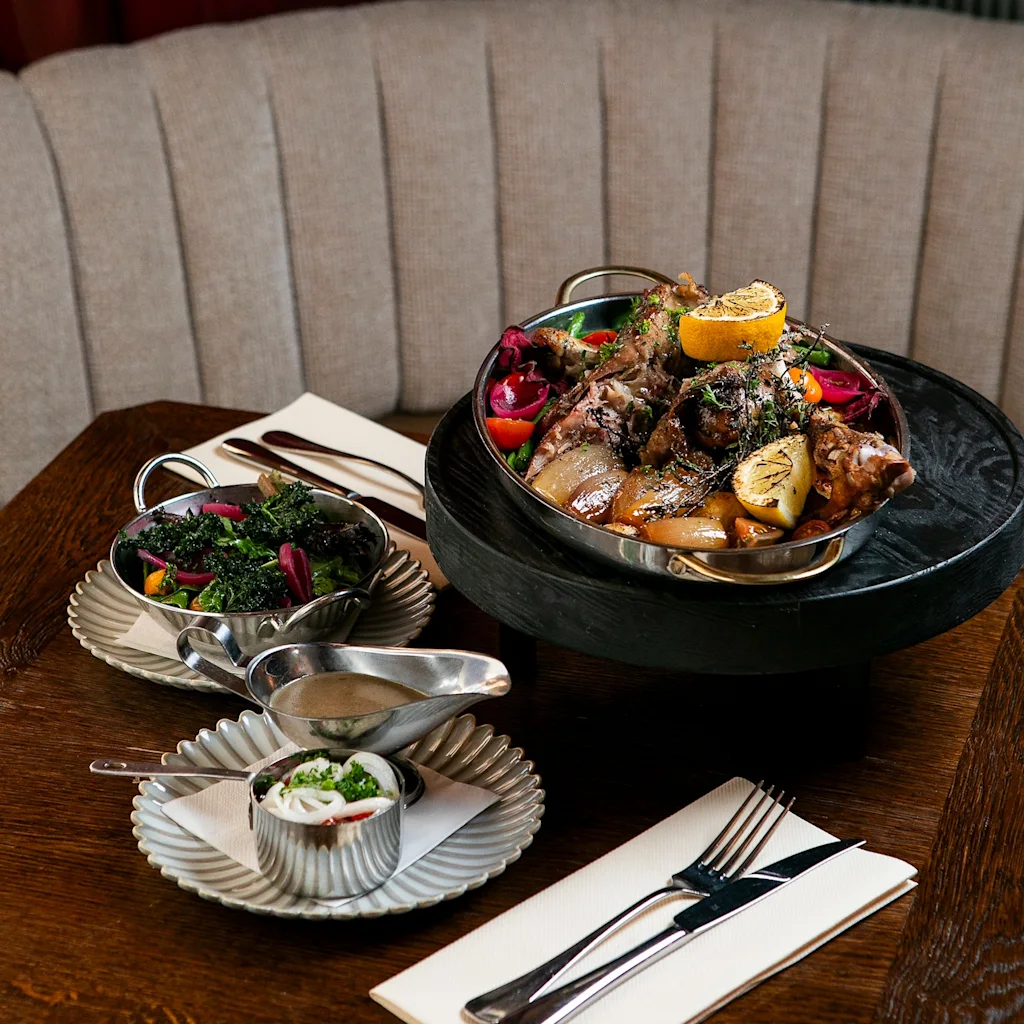 Et lækkert måltid med hovedret, tilbehør og saucer, smukt præsenteret på et træbord i en restaurant.