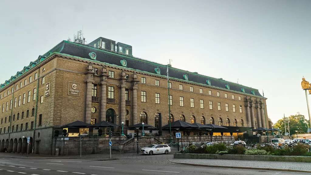 Exteriör vy av Clarion Hotel Post, en ståtlig byggnad med grönt tak och uteserveringar, intill en gata.