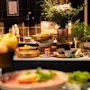 En livlig buffé med frisk frukt, oster og ulike retter, pyntet med et vakkert blomsterarrangement.