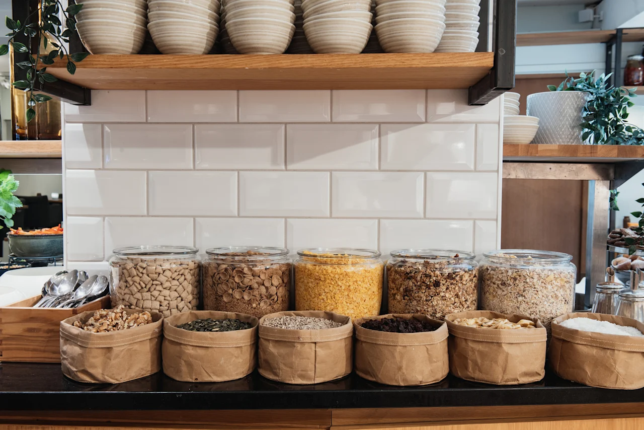 En livlig frukostbuffé på Home Hotel Grand, Helsingborg, med ett urval av flingor, nötter och torkad frukt i burkar och påsar.