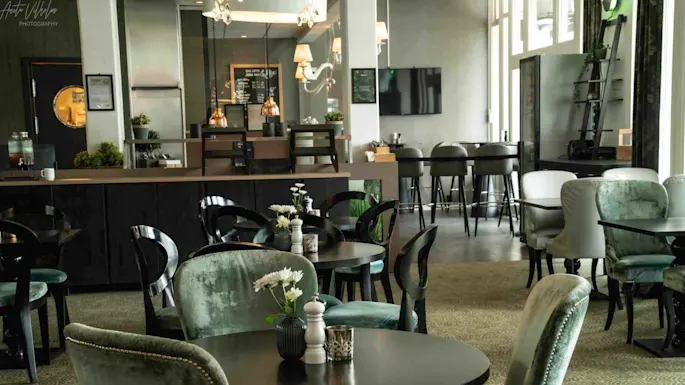 An elegant café with velvet chairs, round tables, and a counter, exuding a vintage charm with modern touches.