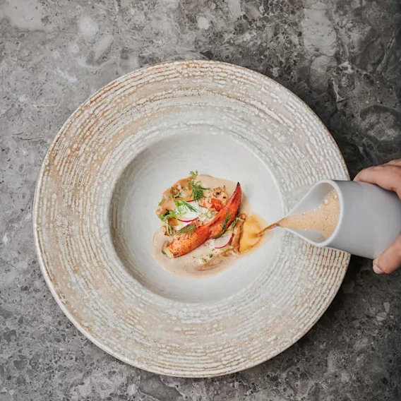 Krämig soppa hälls över en elegant hummerrätt