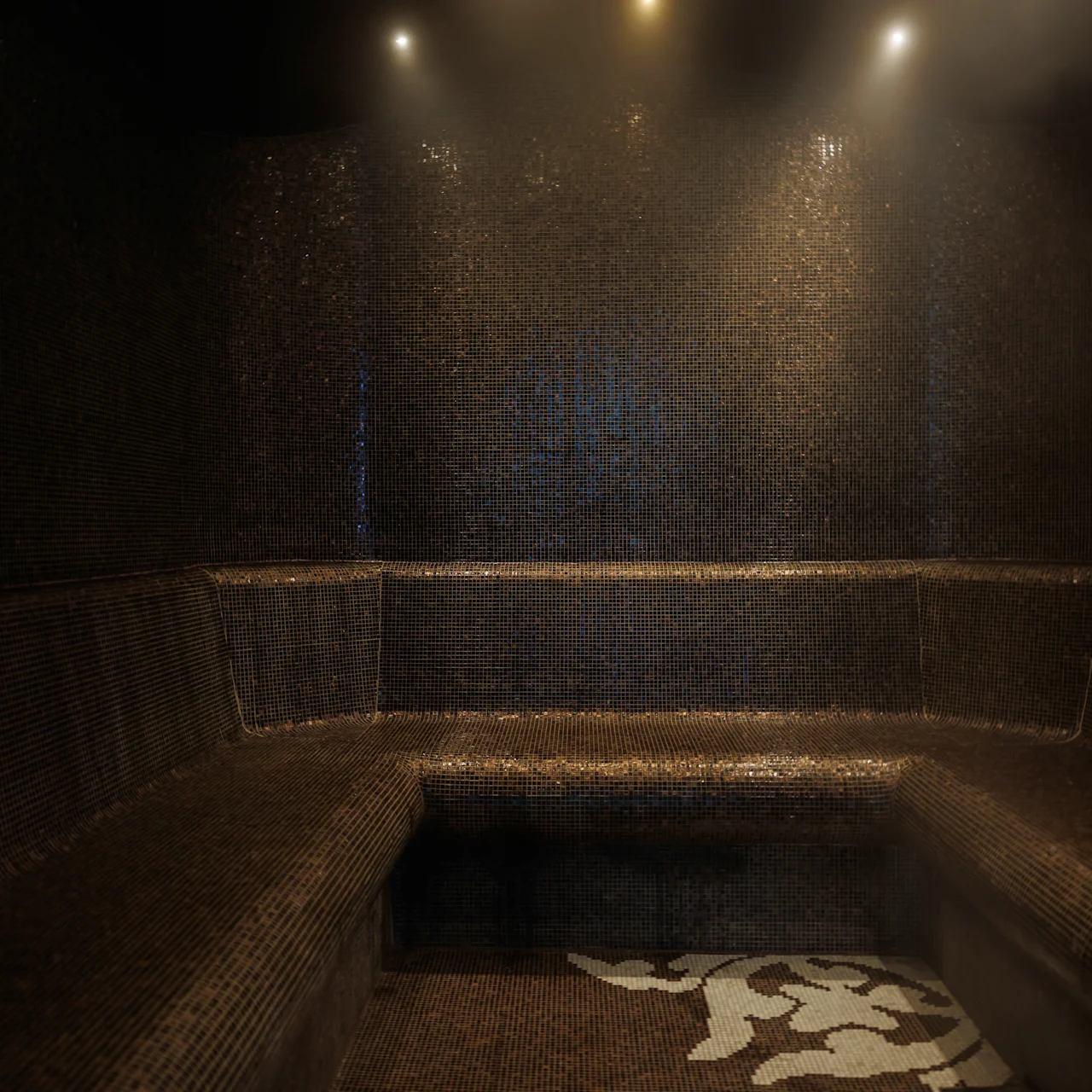 Dark tiled steam room with bench seating lining three walls. Soft, warm lighting creates a relaxing atmosphere, with visible steam enhancing the room's soothing ambiance.