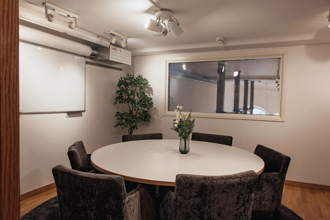 Ett mysigt mötesrum på Home Hotel Grand, Helsingborg, med runt bord, bekväma stolar, whiteboard och blommor.