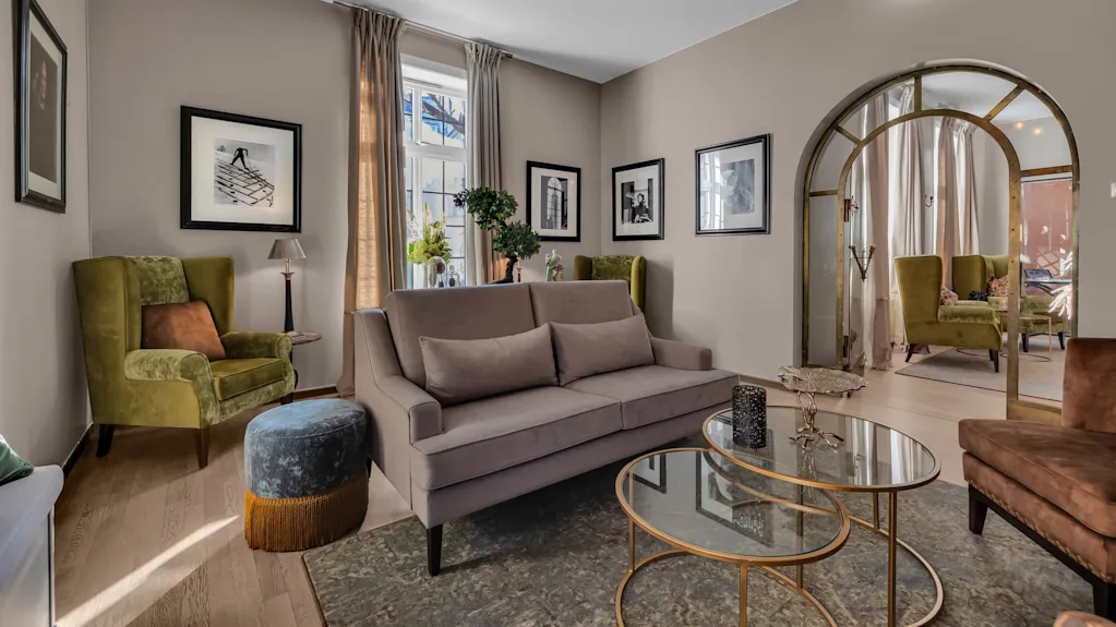 Elegant stue med en sofa, lenestoler og innrammede bilder, som reflekterer en komfortabel, moderne interiørdesign.