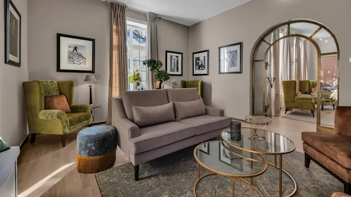 Elegant living room with a sofa, armchairs, and framed pictures, reflecting a comfortable, modern interior design.