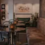 A cozy lounge area with small tables, chairs, and long upholstered benches. Candles glow on the tables, creating a warm ambiance.