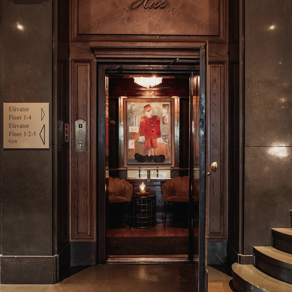 Elevatoren på Home Hotel Grand i Helsingborg. Klassisk elevator med maleri indeni, ved siden af skilt for etager 1-4, 1-2-5 og Gym.