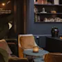 A warm and inviting lounge with plush seating, a fireplace, and shelves. A chalkboard reads Hungry, enjoy.