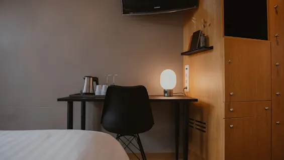 A cozy corner in a hotel room at Home Hotel Uppsala with a desk, chair, lamp, and coffee/tea station, ready for use.