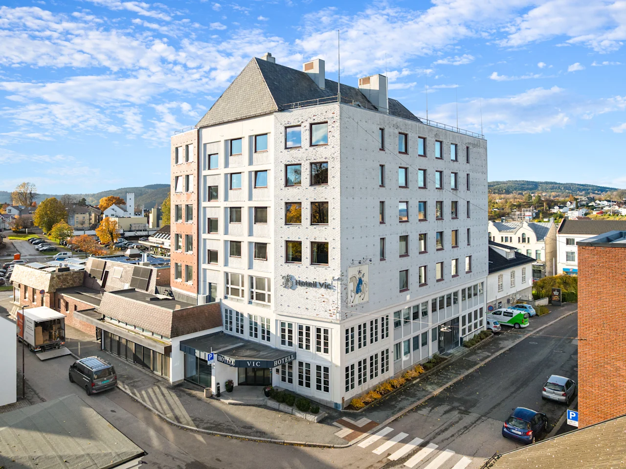 Et lyst hotellbygg i et urbant strøk under en blå himmel med lette skyer