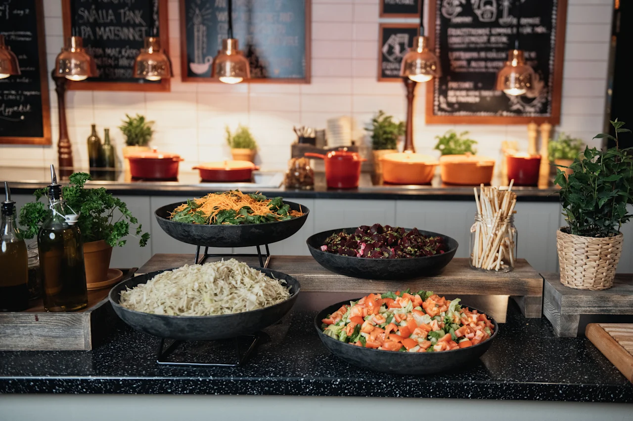 A vibrant buffet spread with fresh salads and dressings. Chalkboards in the background read SNALLA TANK PA MATSUNNET and Appetit.