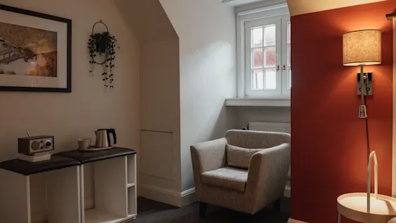 Ett inbjudande hörn i ett rum på Home Hotel Grand, Helsingborg, med en bekväm fåtölj, ett fönster och en tehörna.