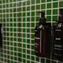 Two dark bottles of LOTION and SOAP mounted on a green tiled wall at Home Hotel Uppsala.