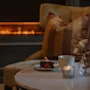 A cozy scene at Home Hotel Kung Oscar with a slice of cake, a warm drink, and a lit candle by a fireplace.