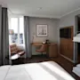 Lyst og moderne familierom med en dobbeltseng, køyesenger, et skrivebord og en behagelig lenestol ved vinduet.
