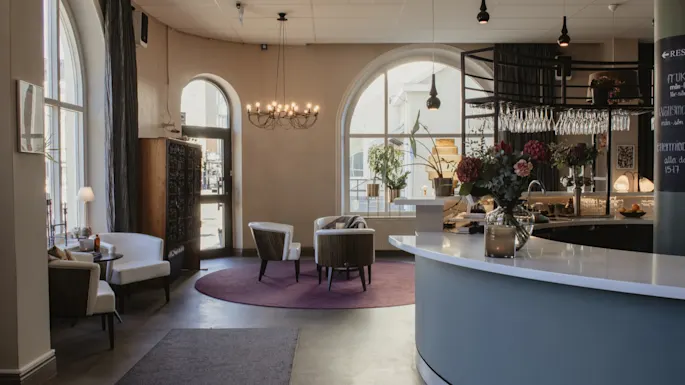 Home Hotel Post lobby med en innbydende resepsjon, komfortable sitteplasser, buede vinduer. Skilt: RESTAURANT, middag 15-17.