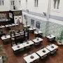 En matsal med prydligt arrangerade bord och stolar, dekorerade med krukväxter, ligger i ett inomhusområde med växtmålningar och en bar. Skyltar säger "Limewood Bar & Restaurant," "Restaurant Enters," och "Welcome Open."