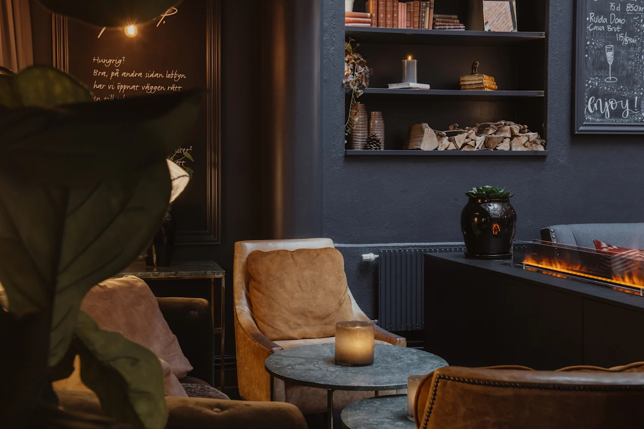 A warm and inviting lounge with plush seating, a fireplace, and shelves. A chalkboard reads Hungry, enjoy.