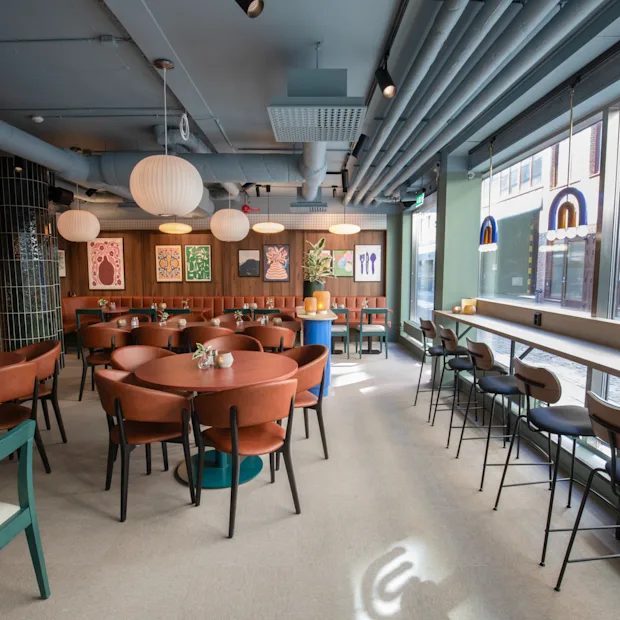 Comfort Hotel City Göteborg. Et moderne restaurantinteriør med runde borde, komfortable stole og et lyst vinduesbarområde.