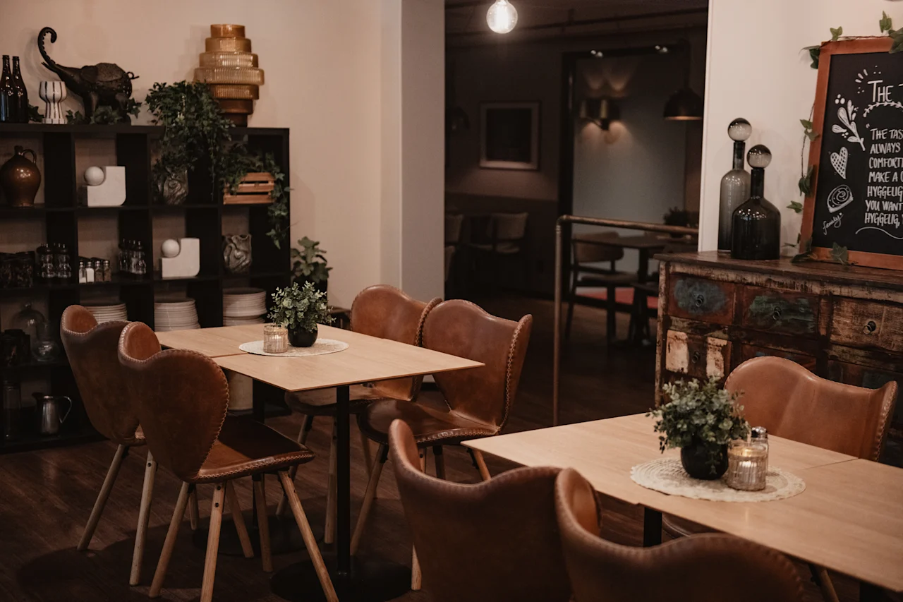 An inviting restaurant interior with warm lighting, wooden tables, leather chairs, and a chalkboard sign: THE TASTE IS ALWAYS COMFORTING.
