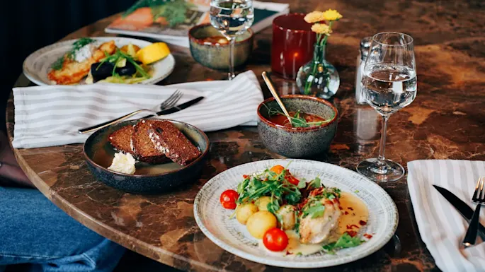 A variety of dishes on a marble table, suggesting a meal in progress at a restaurant.