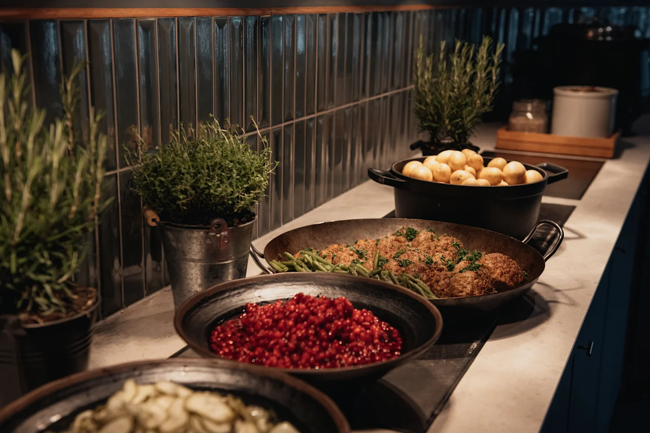 En mysig bufféuppställning med köttbullar, gröna bönor, potatis och bär, förhöjd av färska krukväxter.