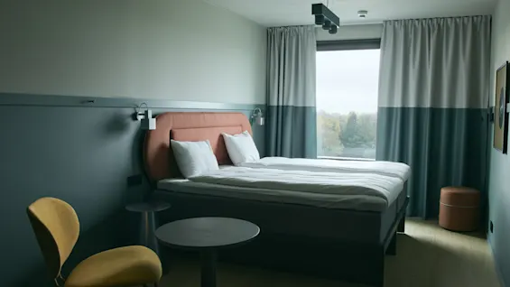 Ett modernt och inbjudande hotellrum på Stopover Hotel Falkenberg, med en bekväm säng och ljus fönsterutsikt.