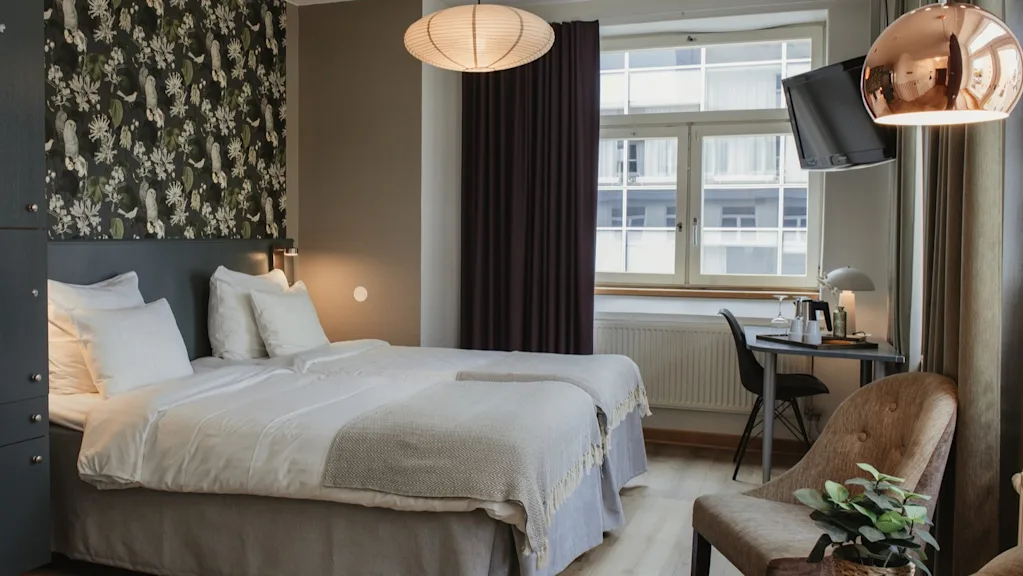 A cozy and inviting hotel room at Home Hotel Uppsala with two comfortable beds, a work desk, and a seating area.