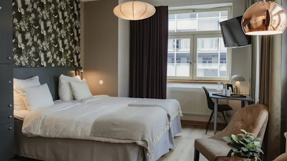 A cozy and inviting hotel room at Home Hotel Uppsala with two comfortable beds, a work desk, and a seating area.