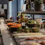 En fargerik buffet med friske salater, skivet kjøtt, oster og frukter, med en liten pakke merket kaviar.