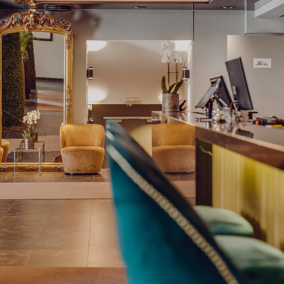 An elegantly decorated reception area with ornate mirror and plush chairs, reflecting a modern workspace.