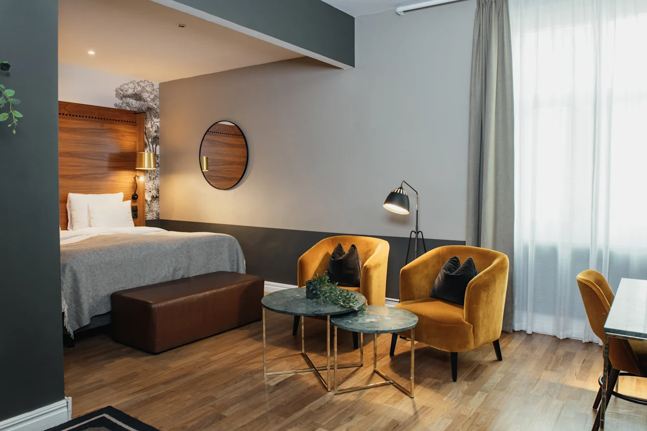 Et stilfullt hotellrom designet for avslapning, med en komfortabel seng og et innbydende sitteområde med to myke lenestoler.