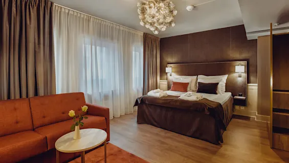 A well-appointed hotel room with a plush bed, elegant lighting, and a cozy sofa, offering a welcoming and comfortable ambiance.
